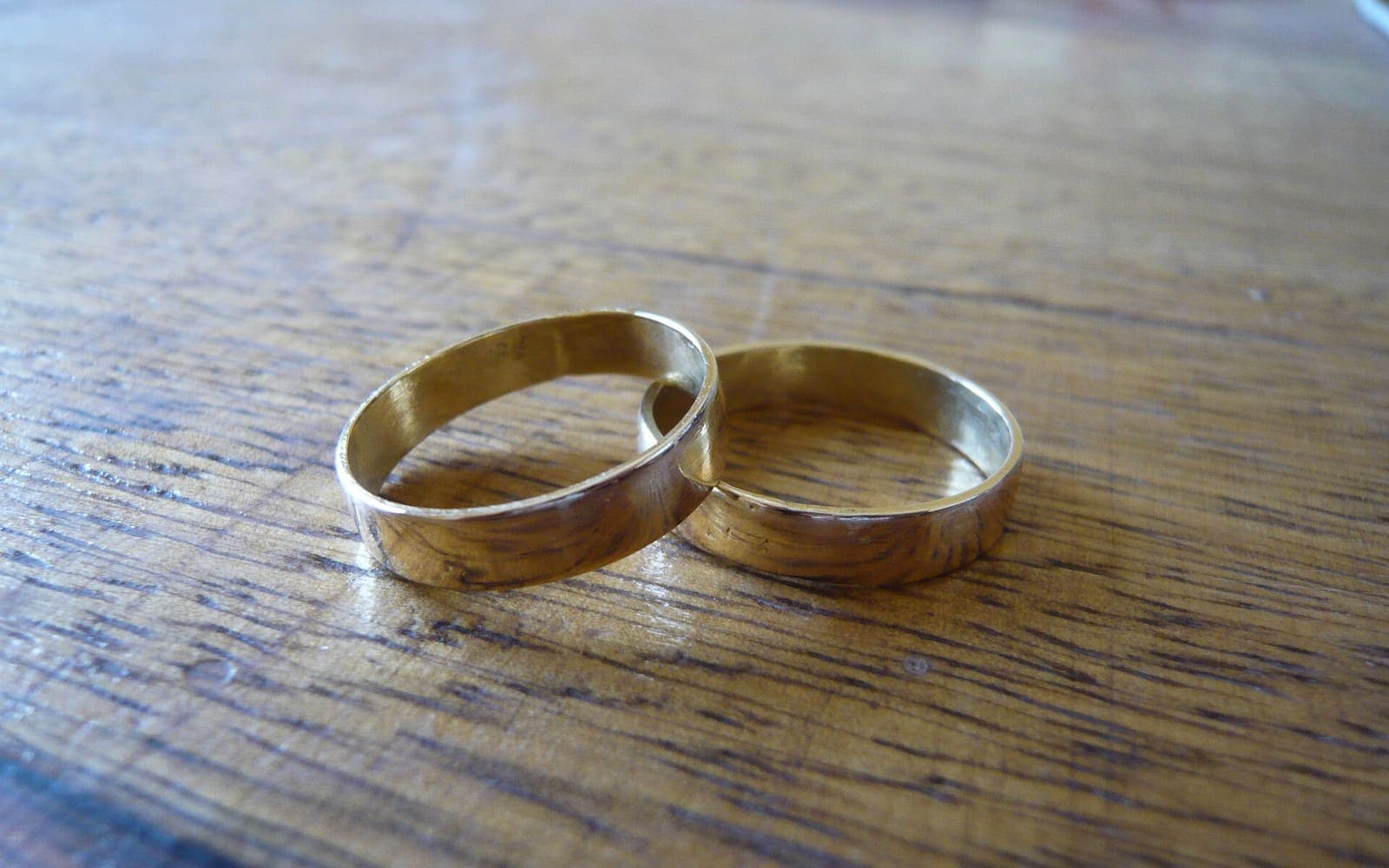 Two gold wedding rings on a wooden table
